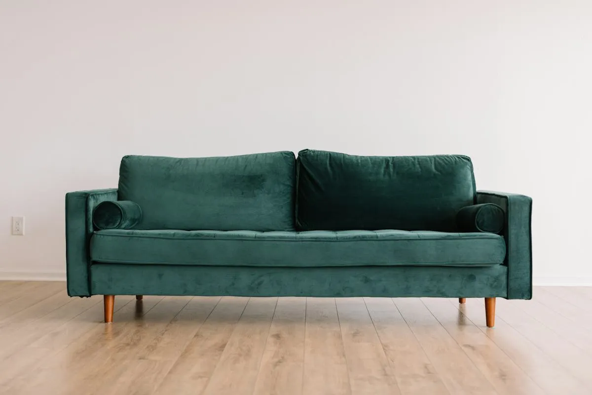 Deep green upholstered sofa on a white wall